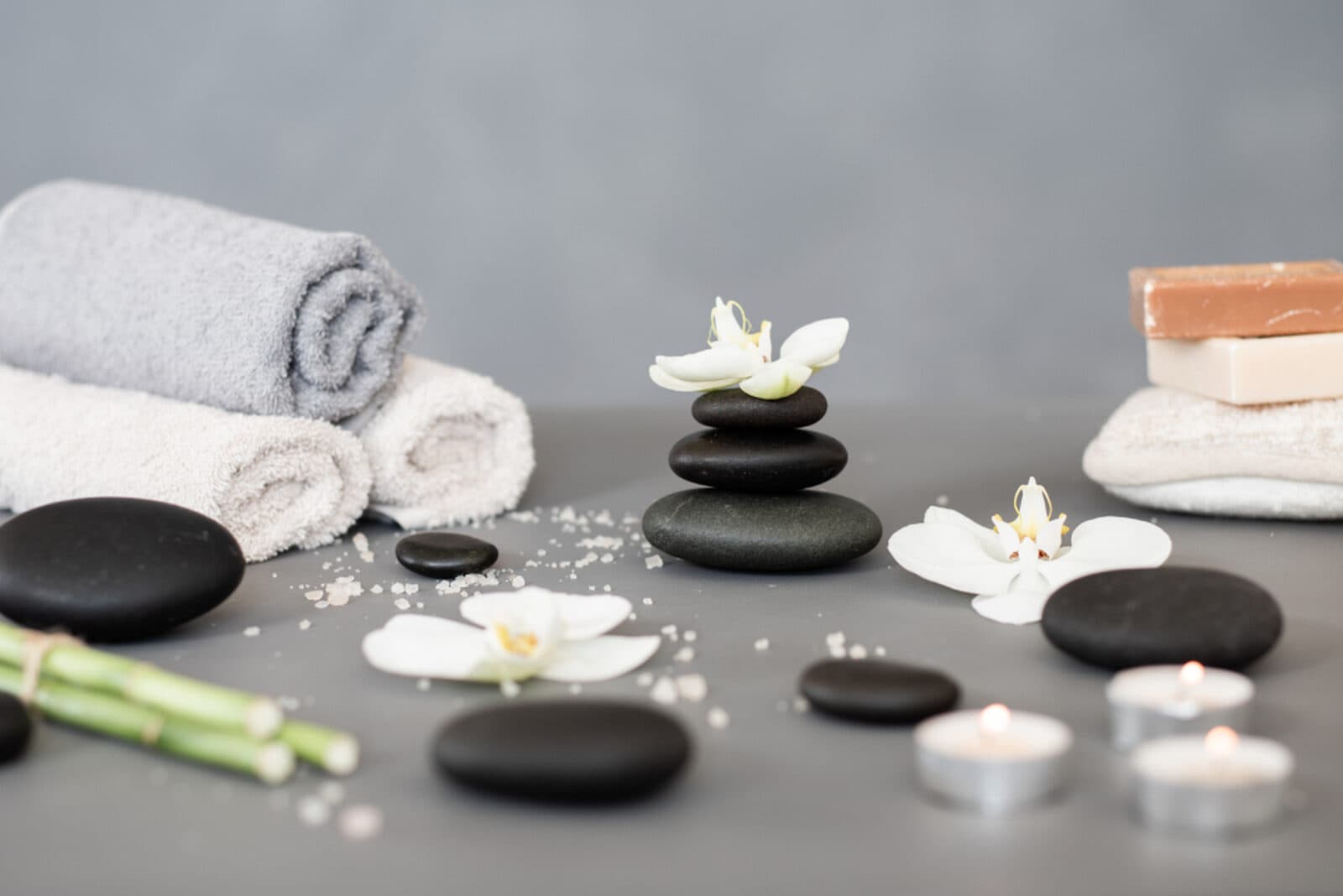 Smooth massage stones, soft towels and orchids arranged for a calm, gentle treatment