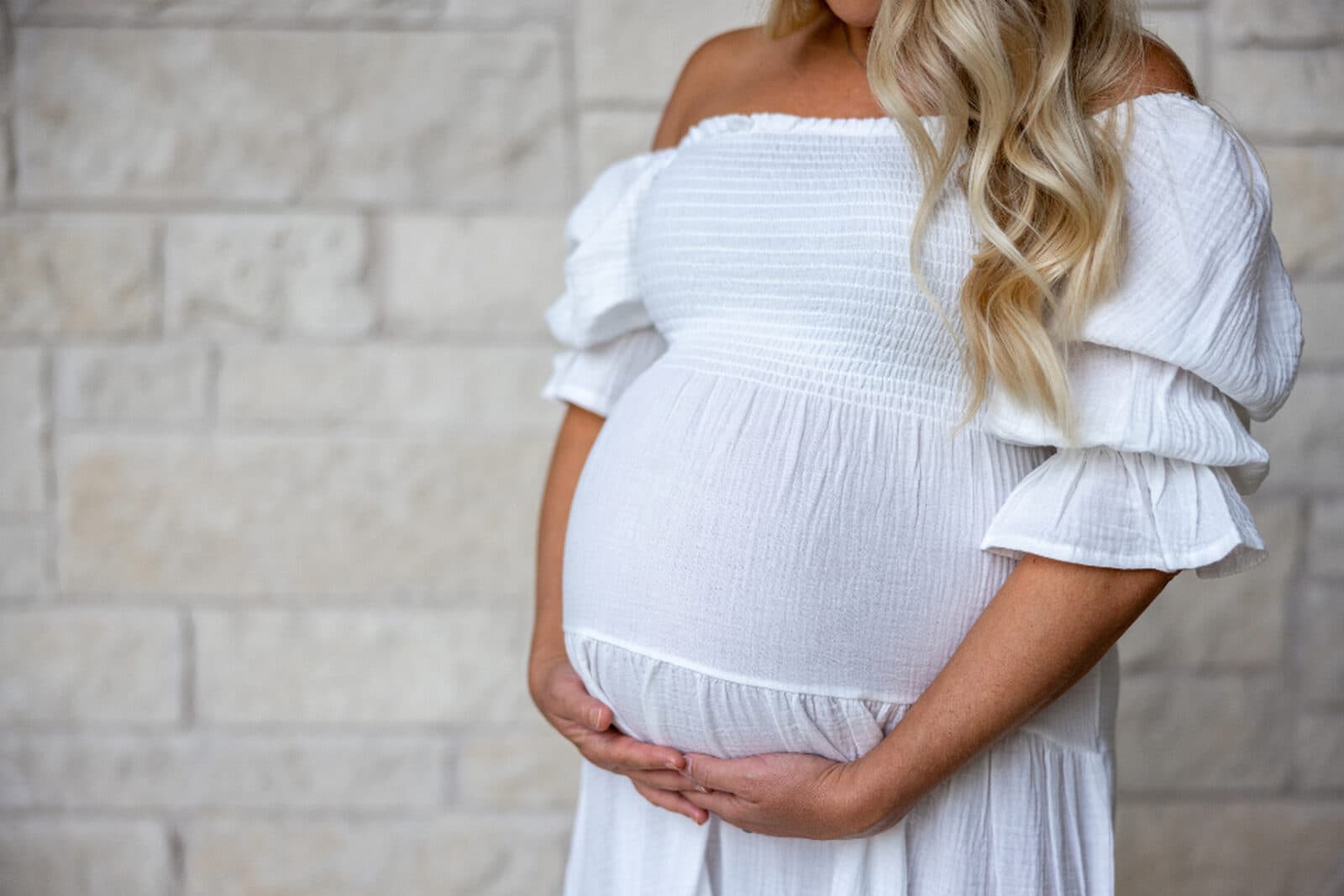A pregnant woman gently cradling her bump in soft, warm light