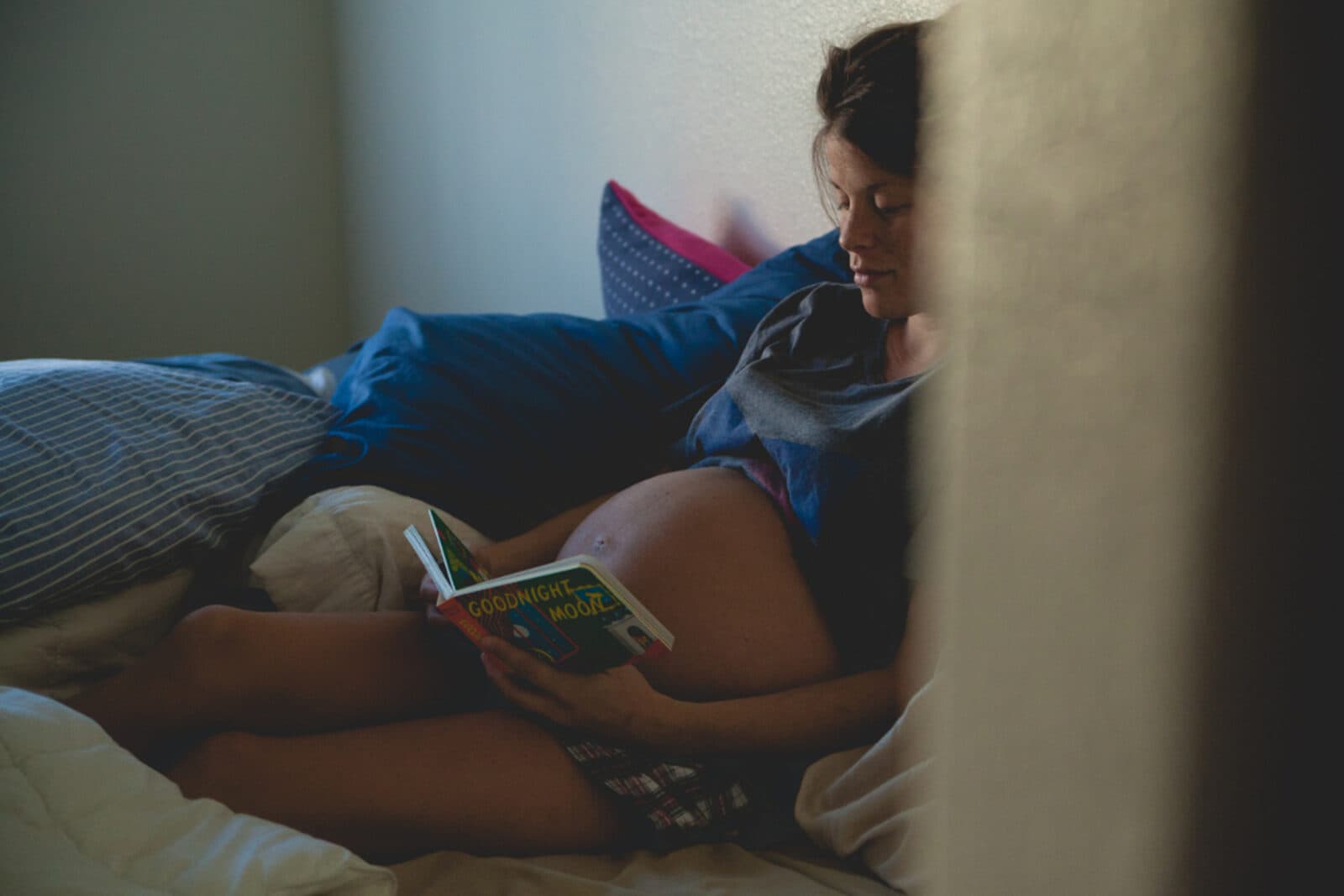 A pregnant woman resting comfortably, propped on soft pillows