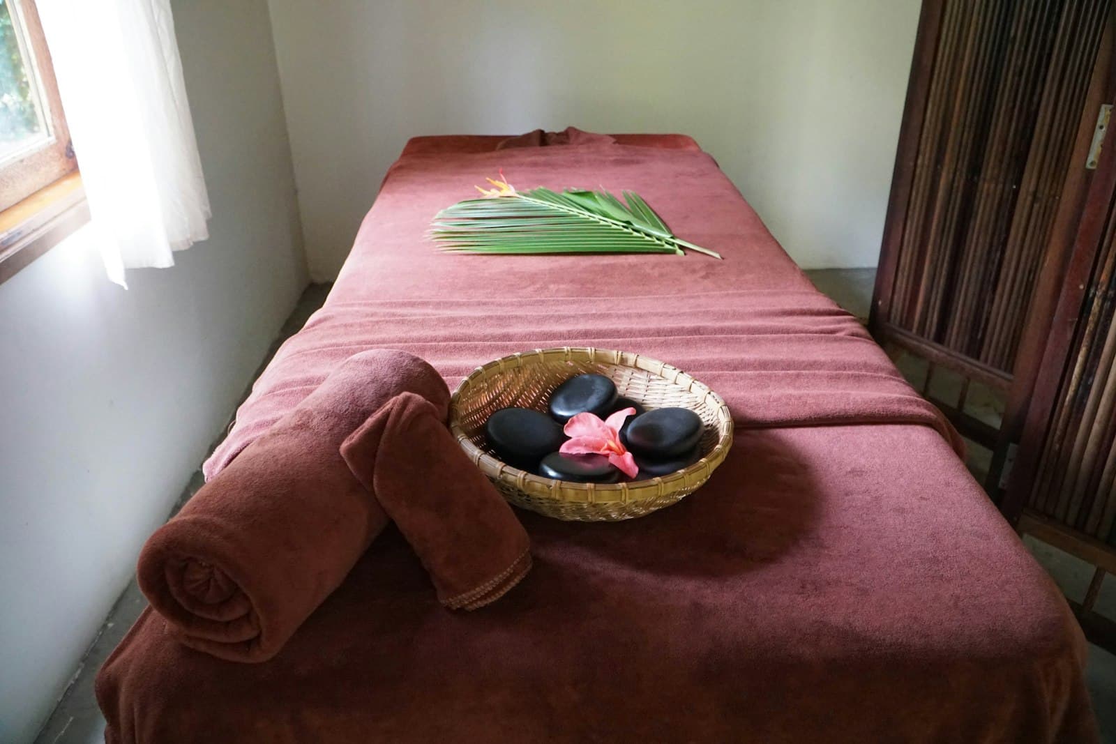 A calm, warmly lit treatment room with a towel-dressed massage table ready