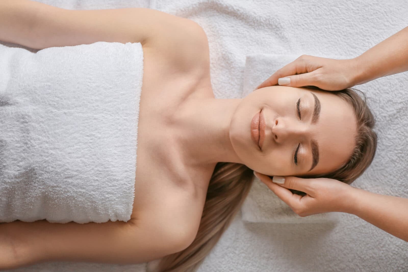 A woman receiving a calming scalp and neck massage with her eyes closed