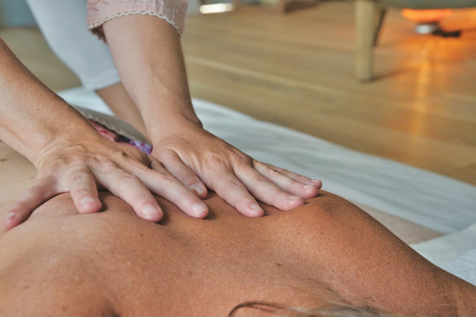 Warm close-up of hands working the shoulders and upper back during a massage